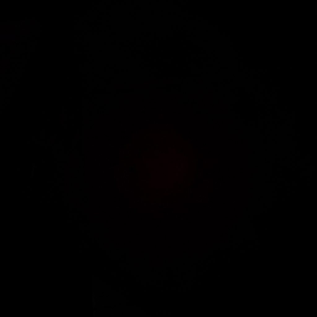 A dark, low-key photograph of a dimly lit study desk with an open notebook and a small lamp casting warm light